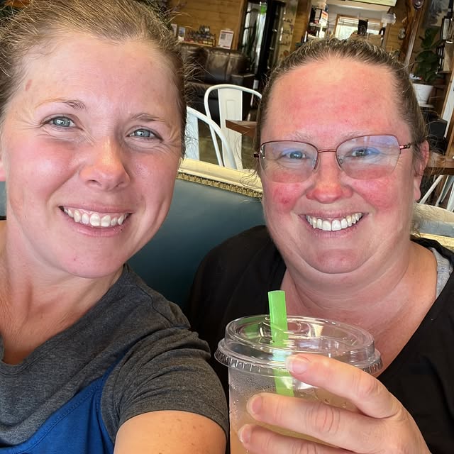 Two smiling customers sharing an iced drink inside fuel. coffee stand's seating area