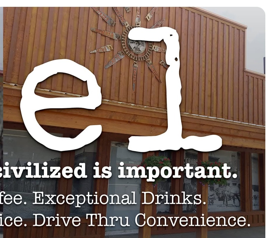 fuel. coffee stand's second building with a metal sunburst emblem and flower boxes over the drive-thru windows